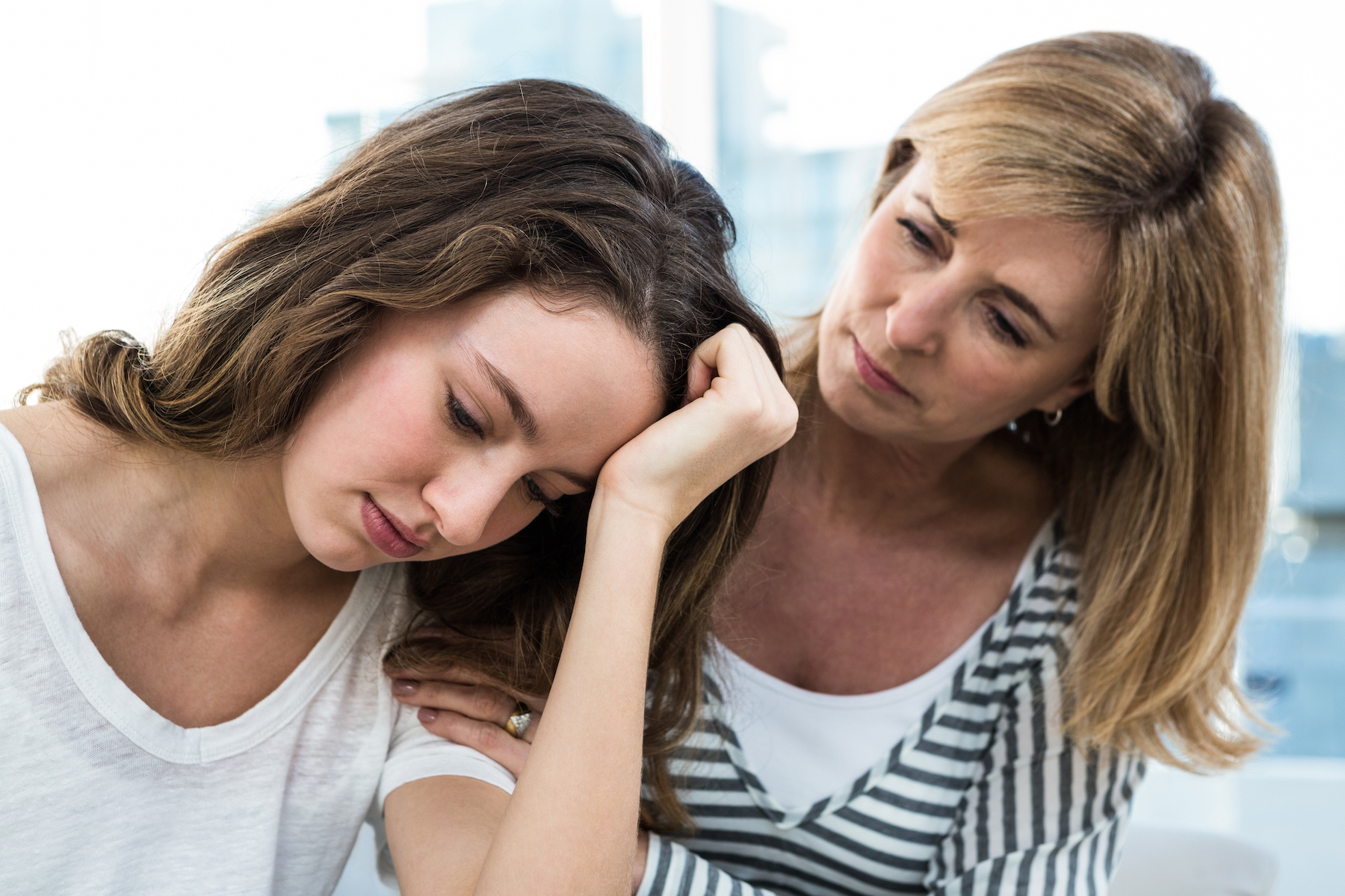 sad daughter against mother on sofa