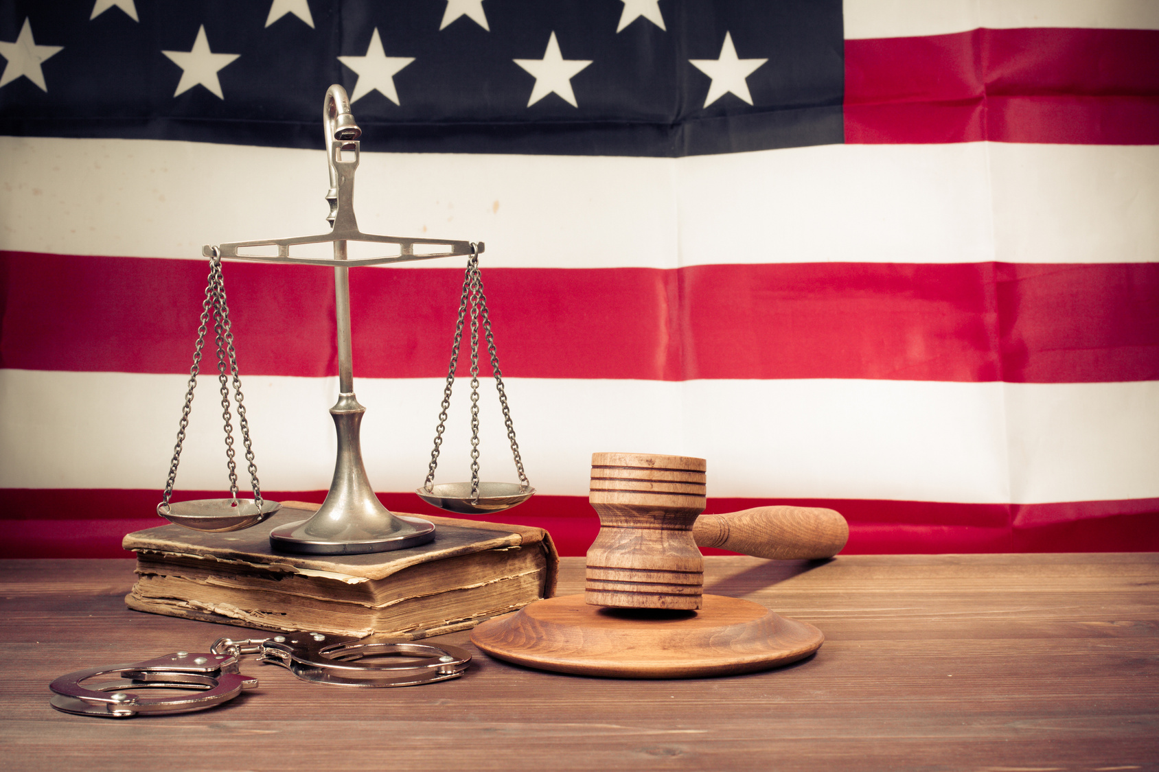 law scales, judge gavel, handcuff, old book front usa flag